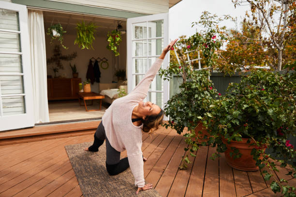 istock Mature woman smiling while practicing yoga on her patio 1216606769