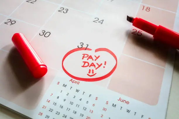 Photo of Payday end of month date on calendar with red marker and circled day of salary