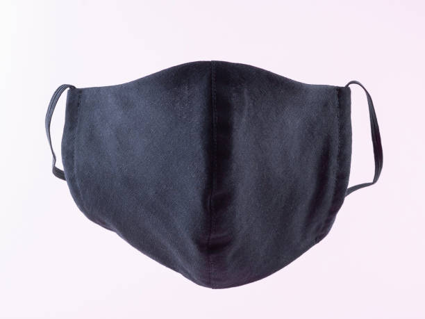 istock Handmade protective mask. Antivirus mask made from cotton. Black stylish face mask during a pandemic virus COVID-19. Face protective mask on a pink background 1216607861