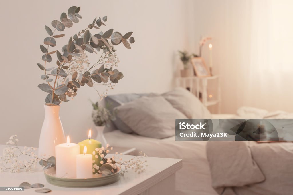 burning candles and eucalyptus in  vase in white bedroom Candle Stock Photo