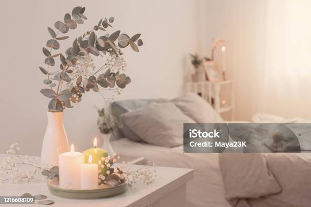 Burning Candles And Eucalyptus In Vase In White Bedroom Stock Photo - Download Image Now