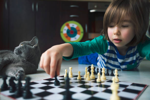 istock Little boy playing chess. Cat next to him. 1216611061
