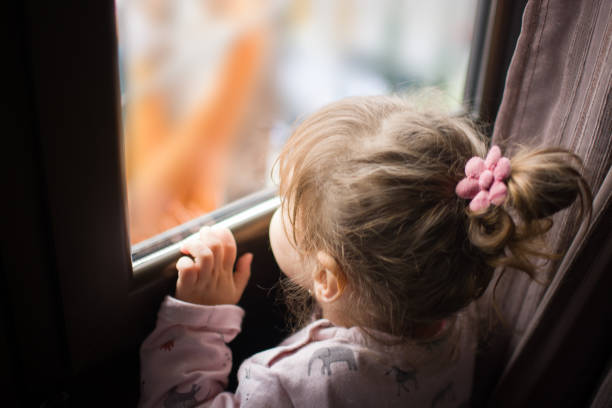 istock Little girl looking out the window 1216612630