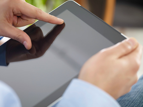 Close up of woman wearing grey casual shirt hand holding and using tablet. Woman chatting about something for social media concept