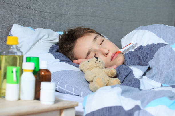 istock Sick child boy lying in bed with a fever, resting 1216615946