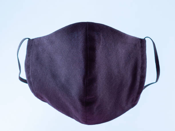 istock Handmade protective mask. Antivirus mask made from cotton. Black stylish face mask during a pandemic virus COVID-19. Face protective mask on a blue background 1216616079