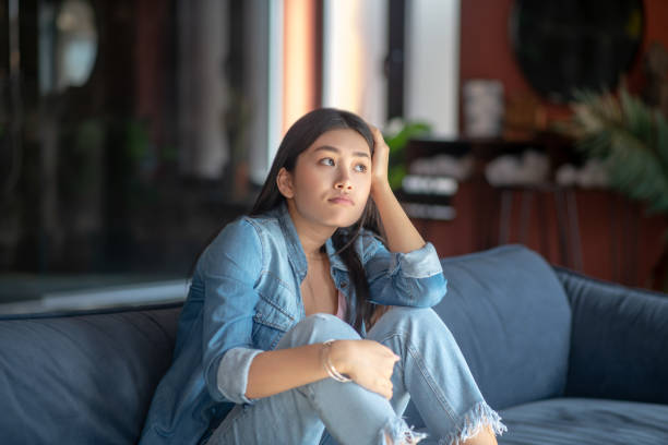 istock Sad young woman sitting on sofa, resting her head on her hand 1216616945
