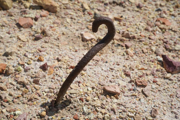 A rusty spike sticks out of the dirt stock photo