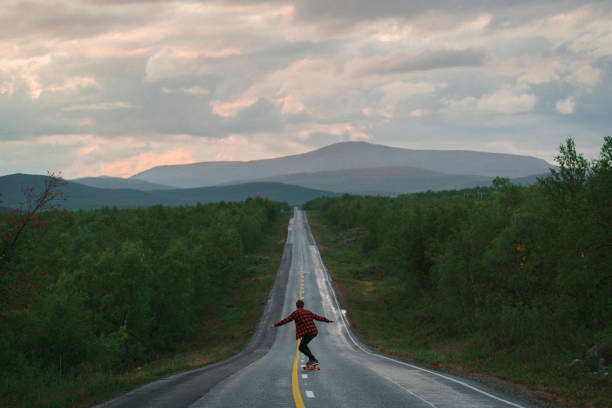 mann longboarding auf der straße in finnland - longboard skating stock-fotos und bilder