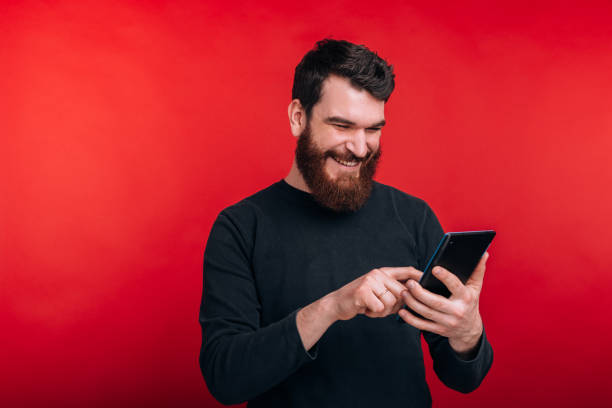 istock happy man surfing on internet with tablet standing over red background 1216622620