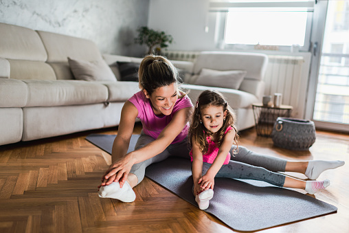 Shot of a young mother practicing yoga with toddler daughter at home. Illness prevention during COVID-19 isolation.