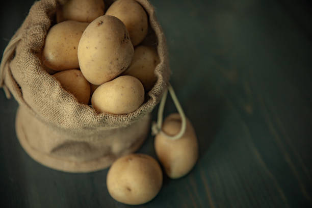 istock Potatoes in sackcloth on rustic wooden background 1216624321