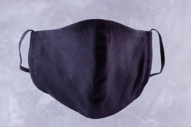 istock Handmade protective mask. Antivirus mask made from cotton. Black stylish face mask during a pandemic virus COVID-19. Face protective mask on a grey background 1216624483