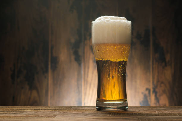 istock Light beer in glass with foam on wooden with copy space 1216628424