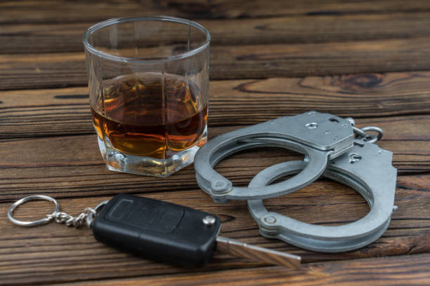 стакан алкоголя с ключами от машины и наручниками. понятие алкоголизм, преступность, арест. вождение в нетрезвом виде - designated driver стоковые фото и изображения