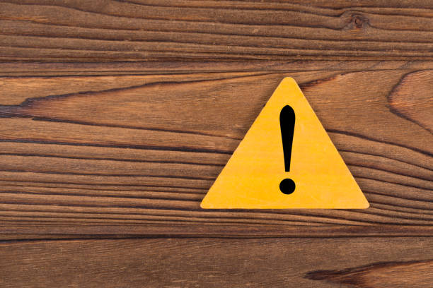 istock Exclamation mark on a yellow triangle background on a wood texture, copy space for design or text. 1216632483