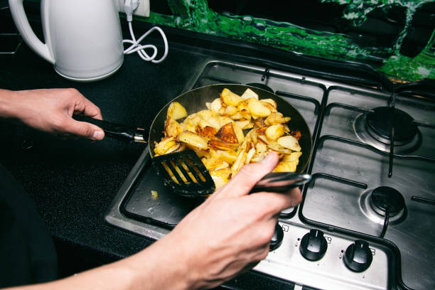 Young attractive cook fries potatoes.