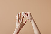Partial view of woman removing nail polish with cotton pad isolated on beige