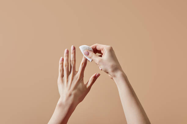 Partial view of woman removing nail polish with cotton pad isolated on beige Partial view of woman removing nail polish with cotton pad isolated on beige nail polish stock pictures, royalty-free photos & images
