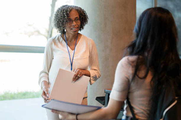 Unrecognizable student speaks with mature female college professor The mature adult female college professor takes time to listen to the unrecognizable young adult female student. community college stock pictures, royalty-free photos & images