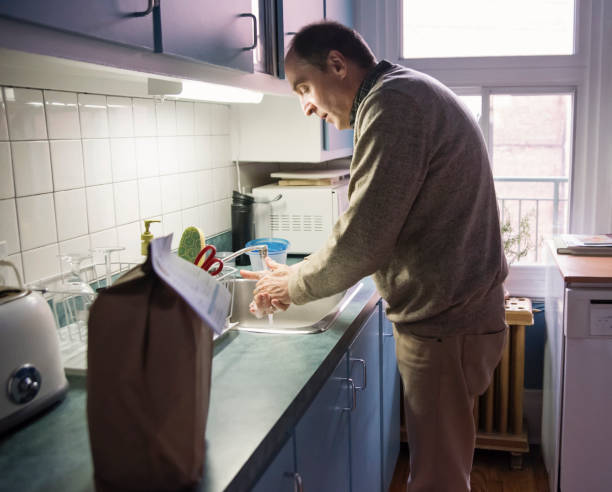 istock Senior man washing hands with delivered food on counter. 1216637069
