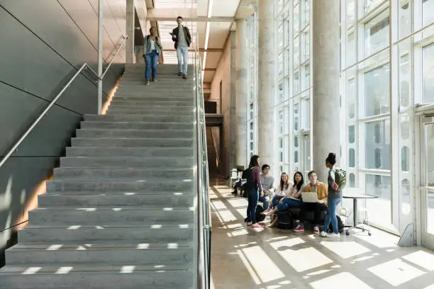 Photo of College students descend indoor staircase