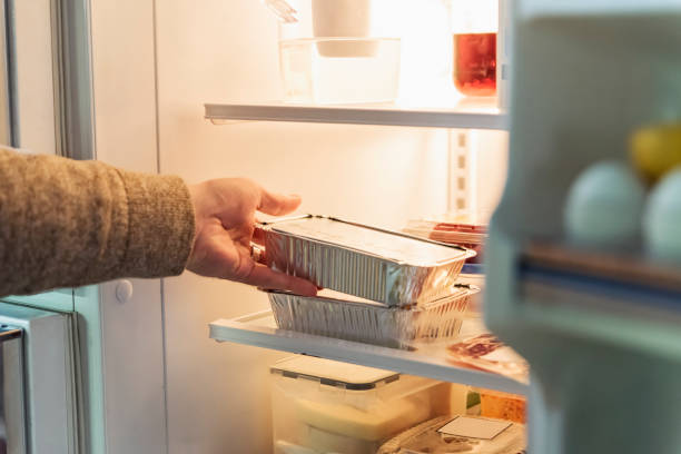 Man's hand taking takeout meal out of refrigerator.