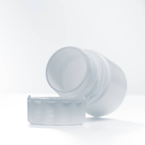 白い背景に水平に分離蓋の近くに横たわっている白いペットボトル。 - gel pill ストックフォトと画像