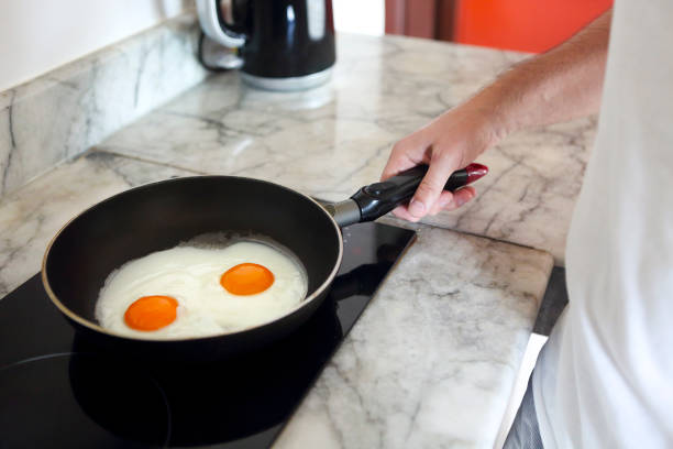 istock Cropped image of man cooking scrambled eggs on frying pan 1216640084