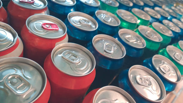 filas de latas de metal de colores con bebida gaseosa en la tienda - lata de refresco fotografías e imágenes de stock