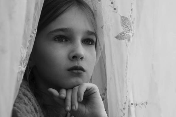 Sad child looking out the window during the isolation and karantina.