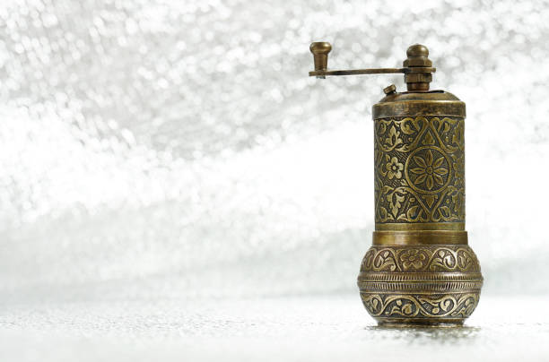 Vintage pepper mill on silver background. Spice grinder. Sample for traditional packing of pepper seed. Close-up photo