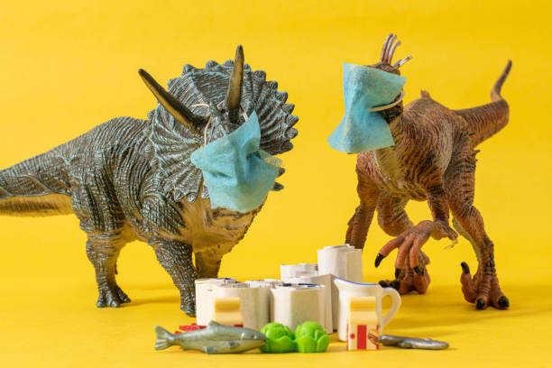 istock Two plastic dinosaurs with face masks and groceries 1216649610