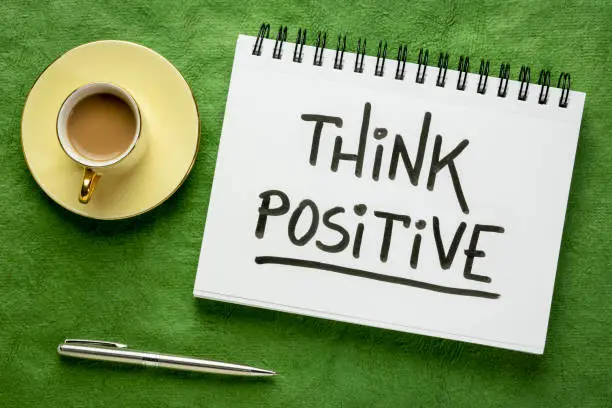 Think positive inspirational handwriting in a sketchbook with a cup of coffee, positivity, optimism and mindset concept