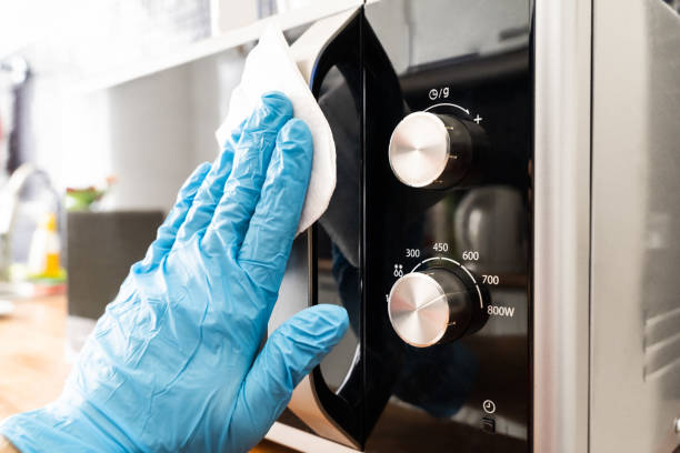 istock Man Wiping Microwave Oven Handle With Sanitizer 1216652300