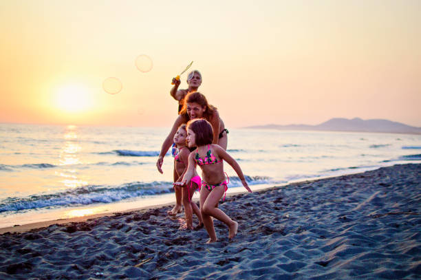 Three generations of women blowing bubbles on sunset on beach