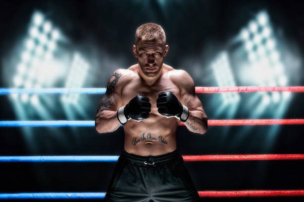 artista marcial mixto posando en el ring contra los focos. concepto de mma, ufc, boxeo tailandés, boxeo clásico. - mixed martial arts combative sport boxing kicking fotografías e imágenes de stock