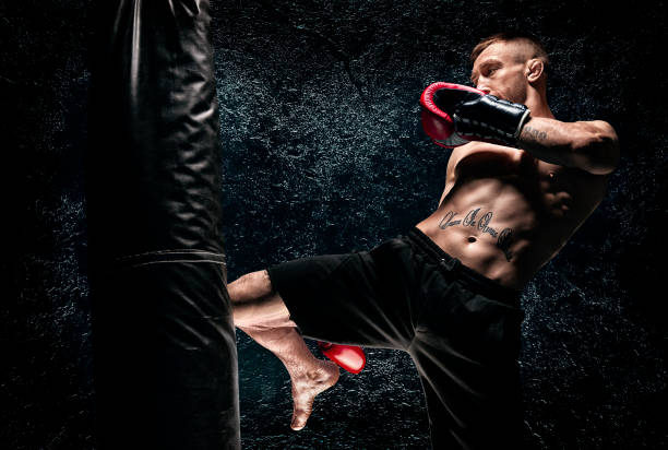 kickboxer hits the bag with his knee. training a professional athlete. the concept of mma, wrestling, muay thai. - kickboxing imagens e fotografias de stock
