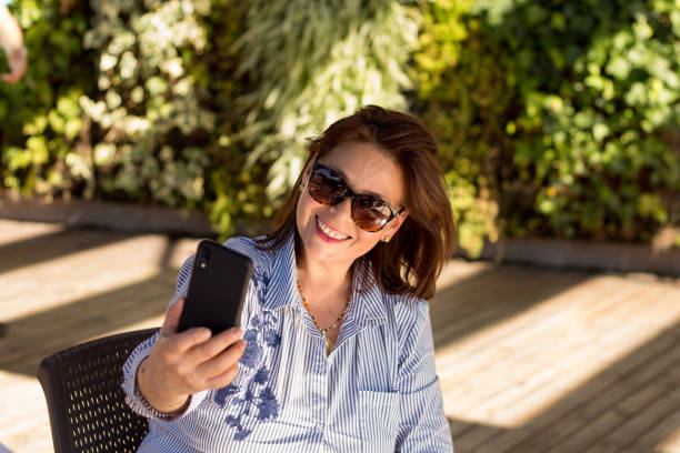 istock Successful and happy mature woman using a samrphone to take a selfie 1216654958