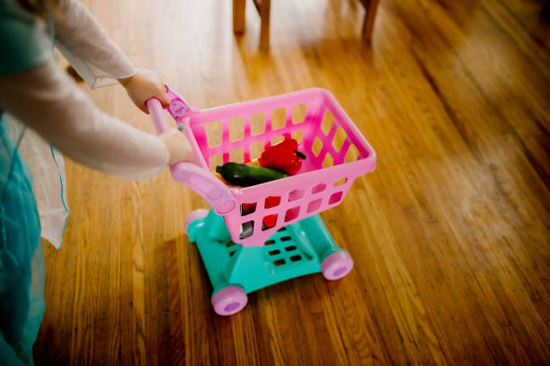 Bambino che spinge il carrello della spesa giocattolo attraverso il legno duro - foto stock