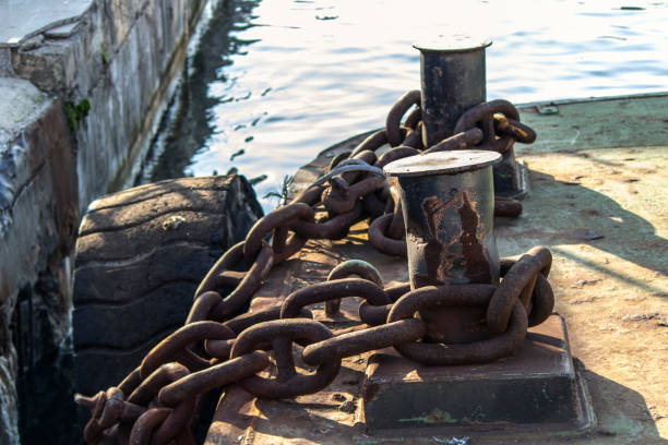 Iron rusty ropes are located on bitts close-up. Painted black Sunny day.