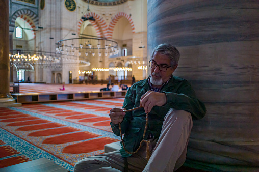 Senior muslim man with prayer beads praying in the mosque