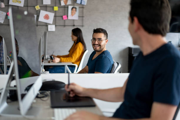 istock Happy coworkers talking from their desks at a creative office 1216664119