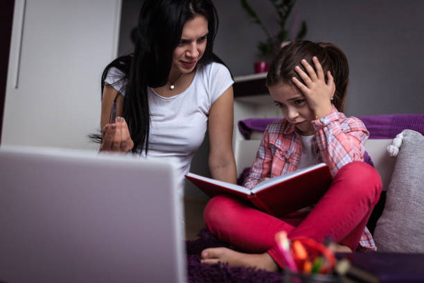 istock Older girl helping young sad girl with an impossible homework task 1216665887