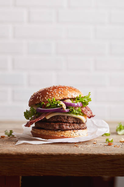 burger z bułeczką sezamową z pierścieniami cebuli i soczystym smażonym mięsem na białym ceglanym tle ściany, gotowy plakat do druku - salad vegetable hamburger burger zdjęcia i obrazy z banku zdjęć