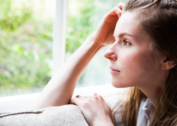 istock Pensive Woman Looking Through the Window 1216665900