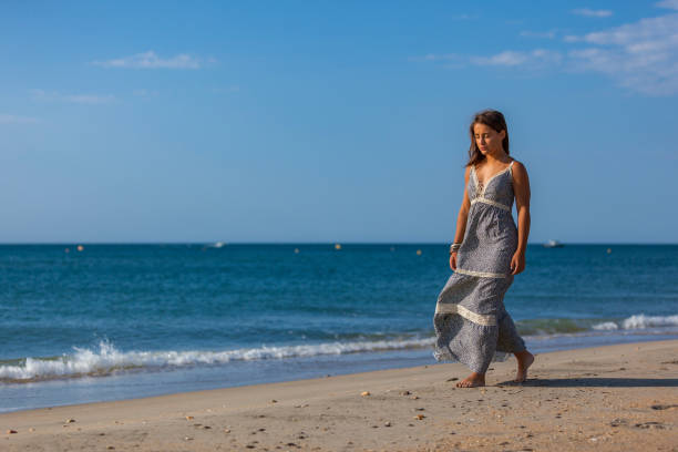 WOMAN WALKING ON THE SAND OF THE BEACH Young woman walking nude foots on the sand of the beach. Joy and freedom concept. mistral wind stock pictures, royalty-free photos & images