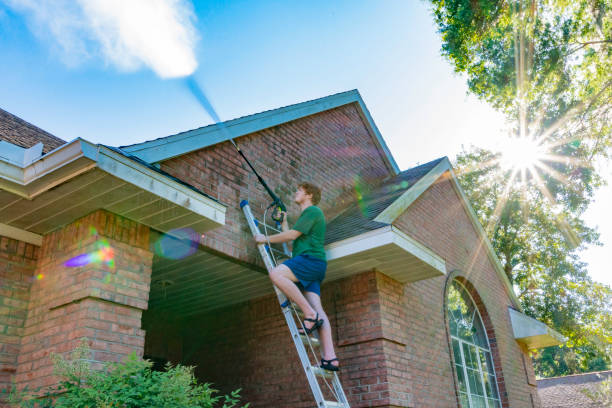 Pressure Washing a Brick House A young man cleans a red brick house exterior. pressure washing house stock pictures, royalty-free photos & images