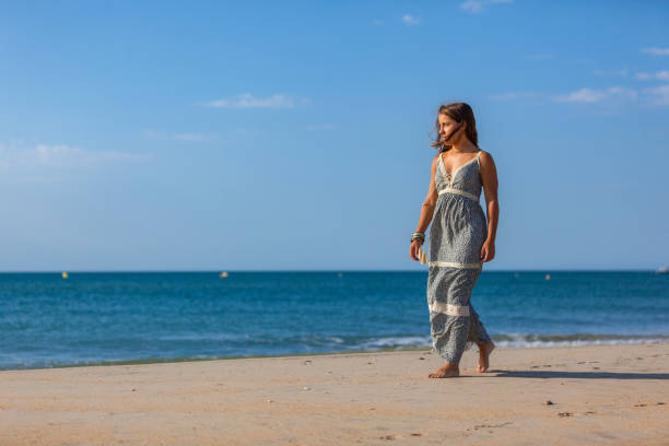 WOMAN WALKING ON THE SAND OF THE BEACH Young woman walking nude foots on the sand of the beach. Joy and freedom concept. mistral wind stock pictures, royalty-free photos & images