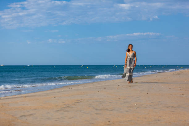 WOMAN WALKING ON THE SAND OF THE BEACH Young woman walking nude foots on the sand of the beach. Joy and freedom concept. mistral wind stock pictures, royalty-free photos & images